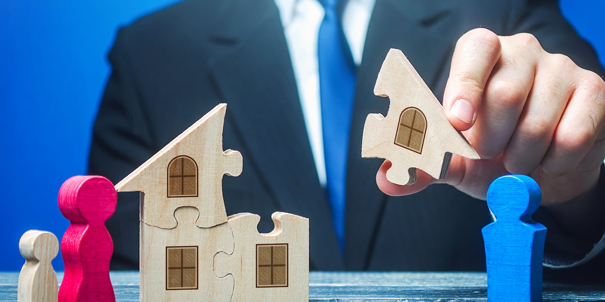 Property division divorce concept showing hands separating house puzzle pieces with family figures
