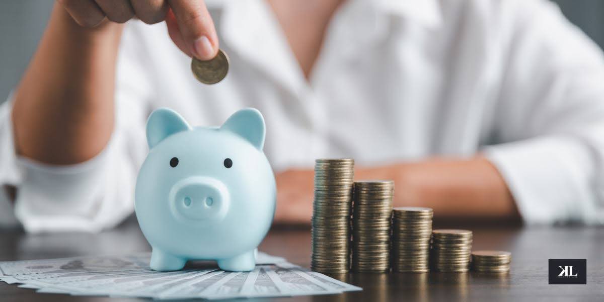 A person placing a coin into a piggy bank beside stacked coins, symbolizing managing retirement accounts in a divorce and securing financial assets.
